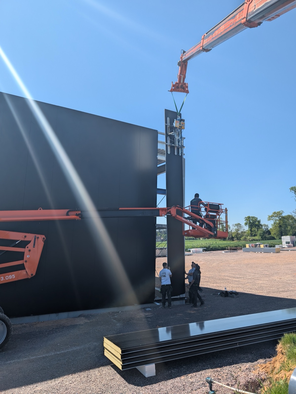 Palonnier à ventouses en action — pose bardage panneaux noirs sur chantier MTLOC